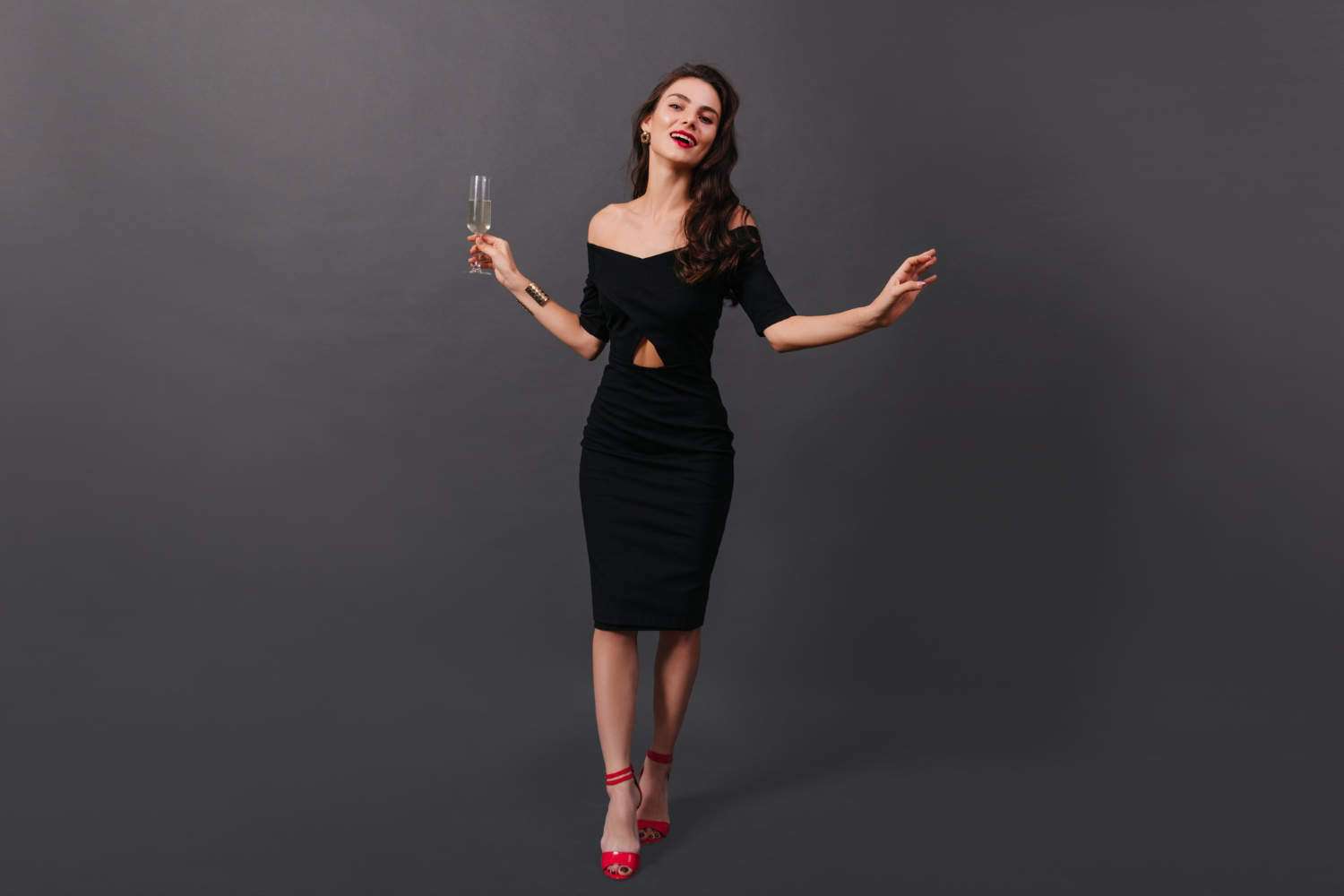 3-tinute cocktail- femeie in rochie neagra si pantofi rosi, pahar in mana, fundal negru (7)
